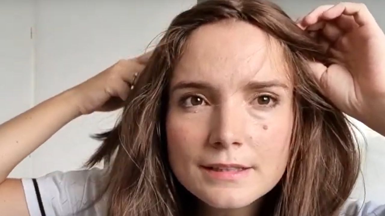 A female is demonstrating how to make a hair topper look natural by mixing with her bio hair at the front hairline